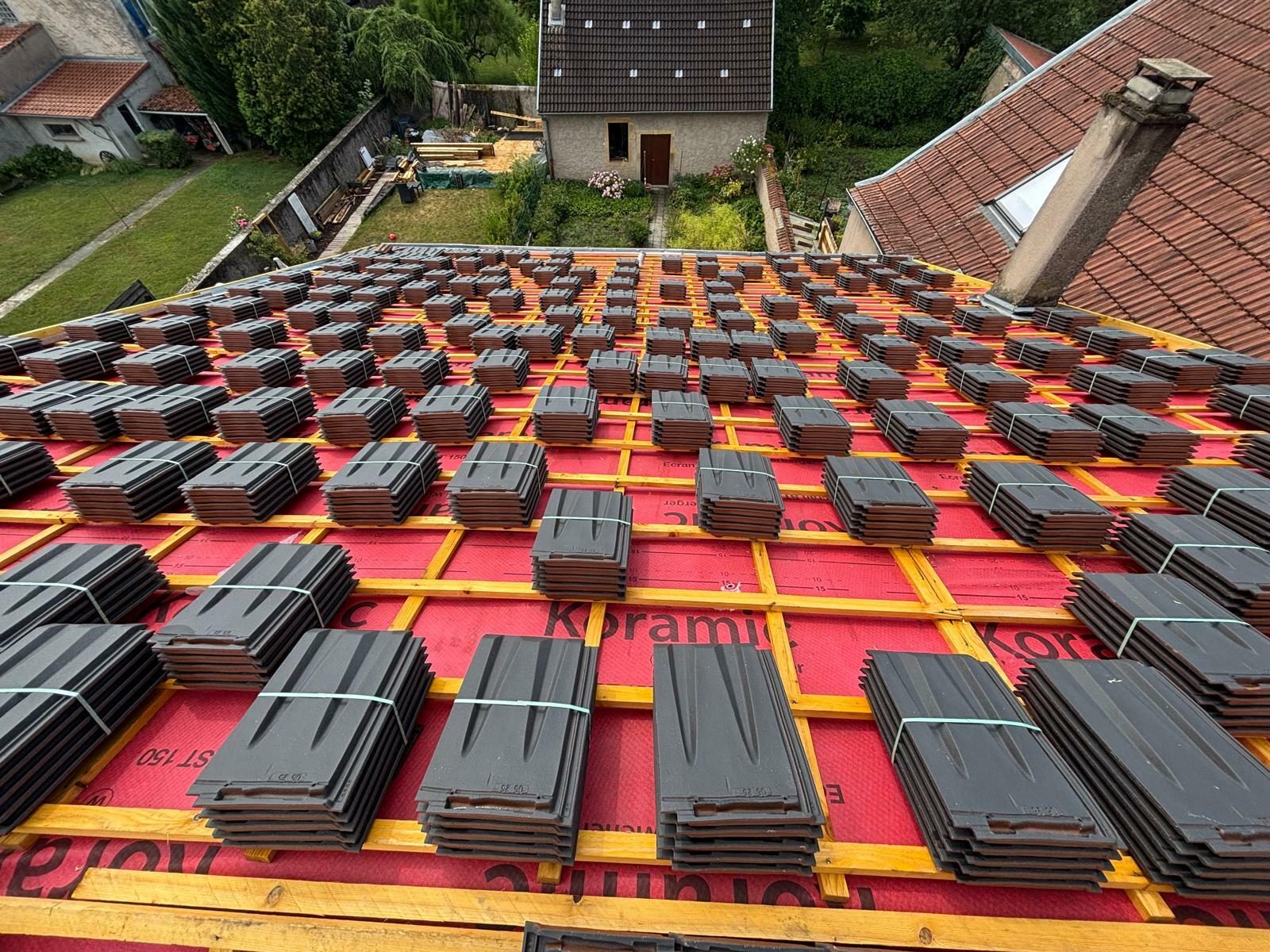 Paquets de tuiles posés sur les liteaux et l'écran sous toiture rouge